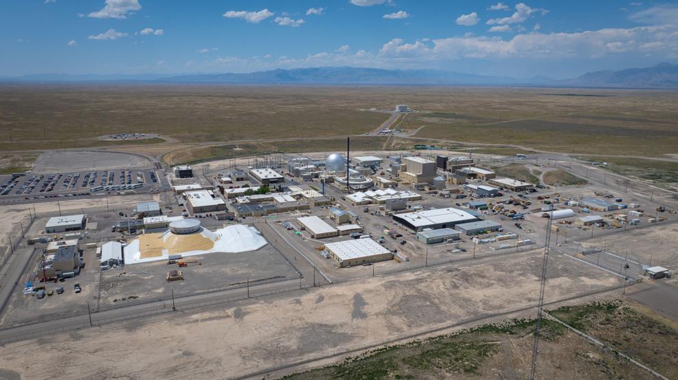 Aerial view of a desert research complex with a domed containment building, laboratory buildings, and mountains on the horizon.